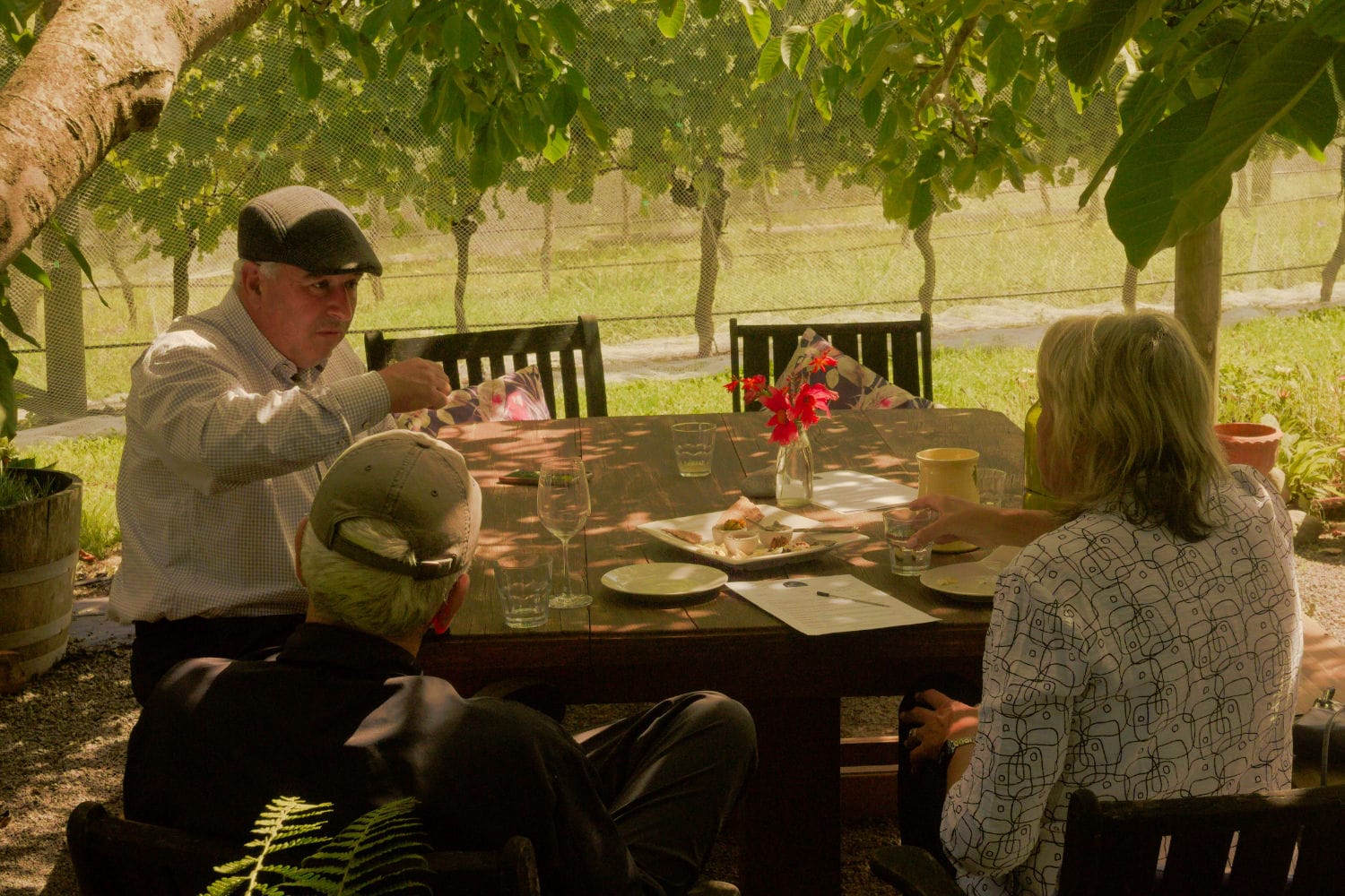Three people are sitting at a table, doing their work and chatting a little.