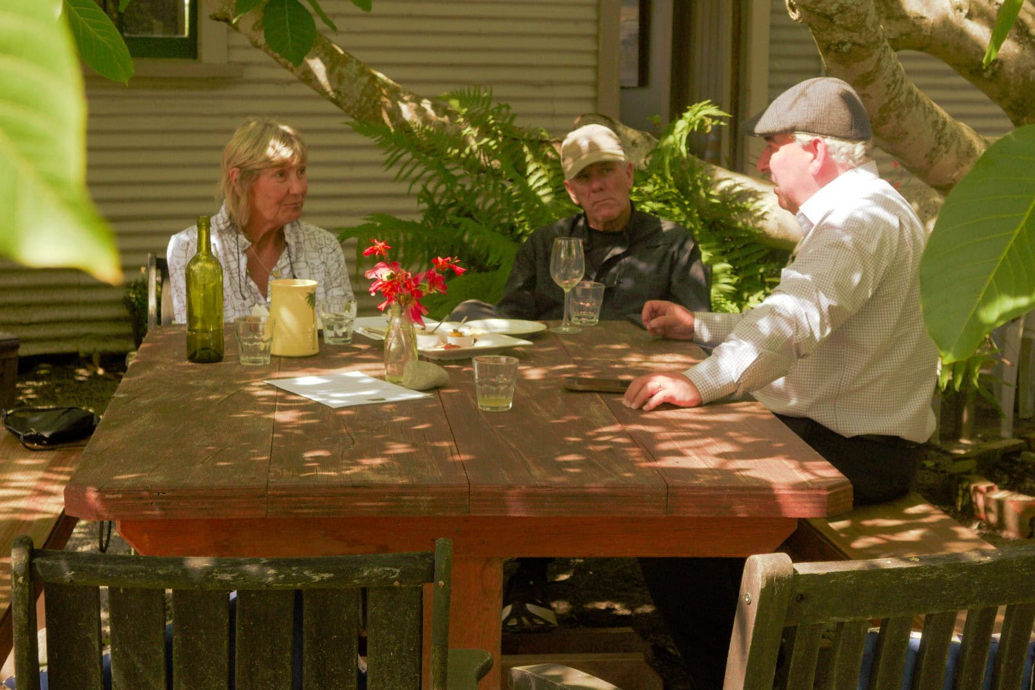 Three people are sitting at a table, doing their work and chatting a little.